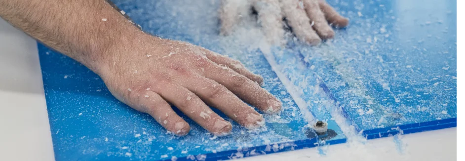 Hände bearbeiten eine blaue Acrylglasplatte